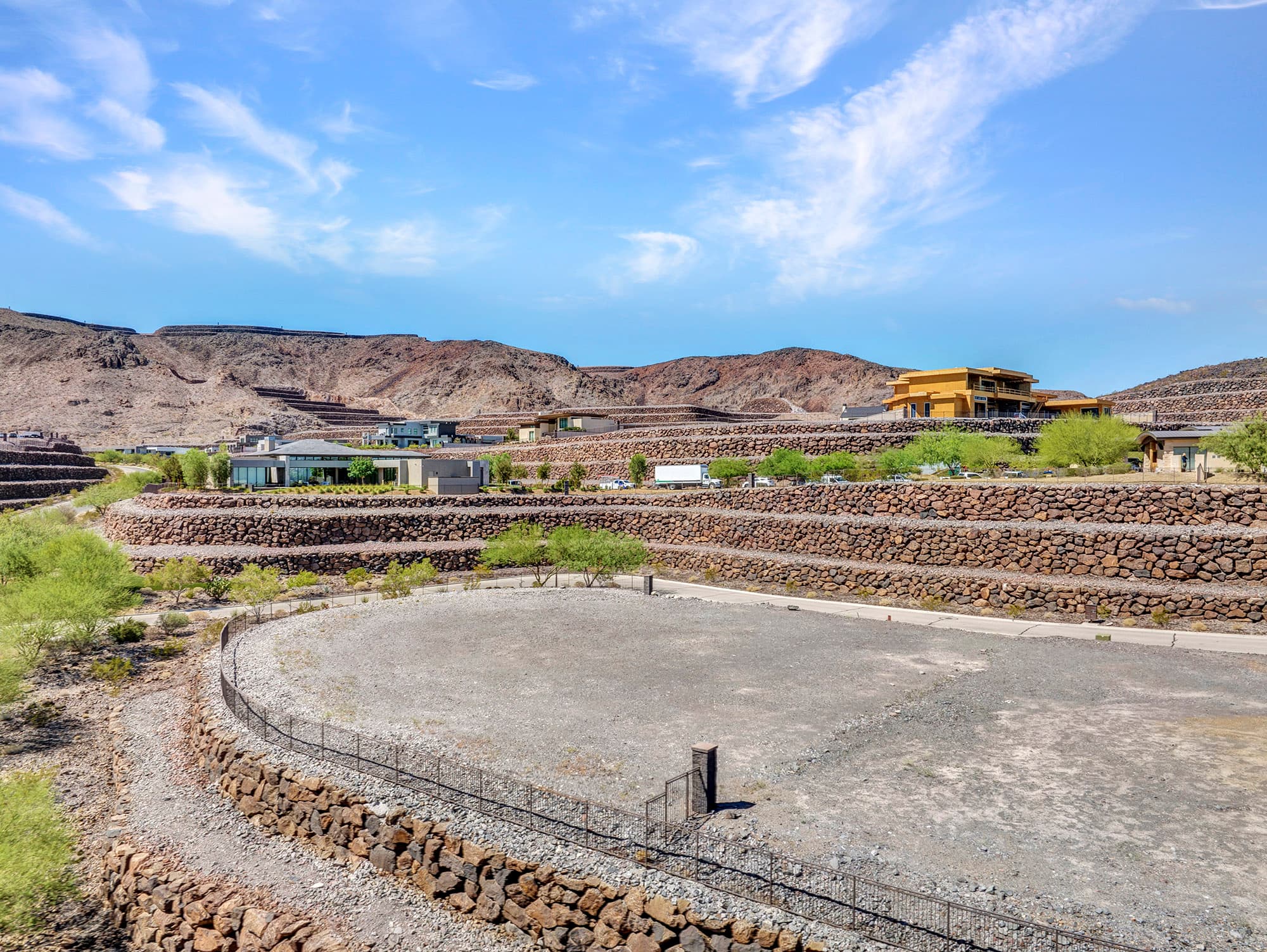 Corner homesite at Ascaya framed by layered rockery walls, neighboring custom homes, and the rugged McCullough Mountain landscape.