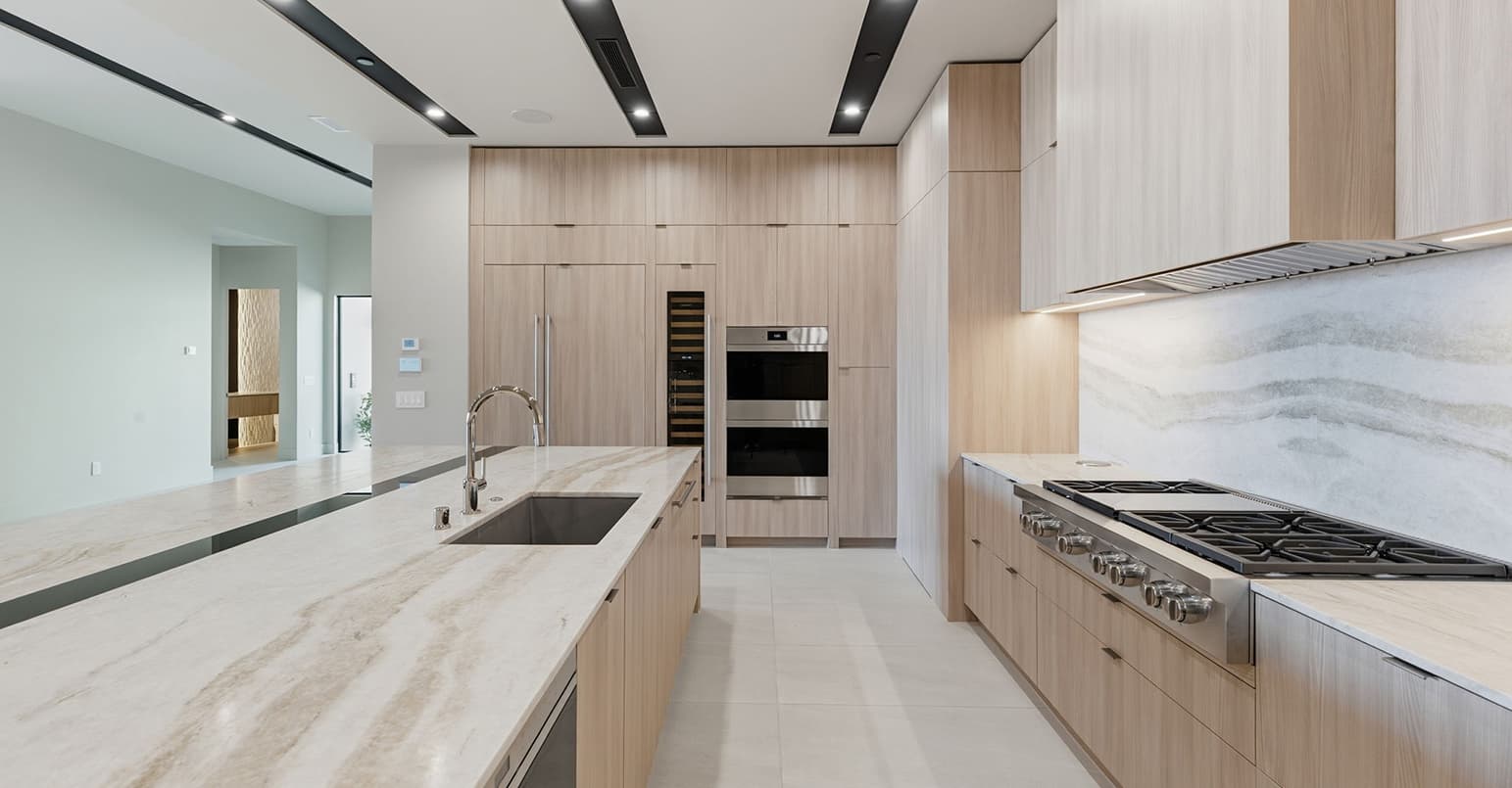 Contemporary chef’s kitchen with waterfall stone countertops, integrated wood cabinetry, premium stainless steel appliances, and minimalist modern finishes