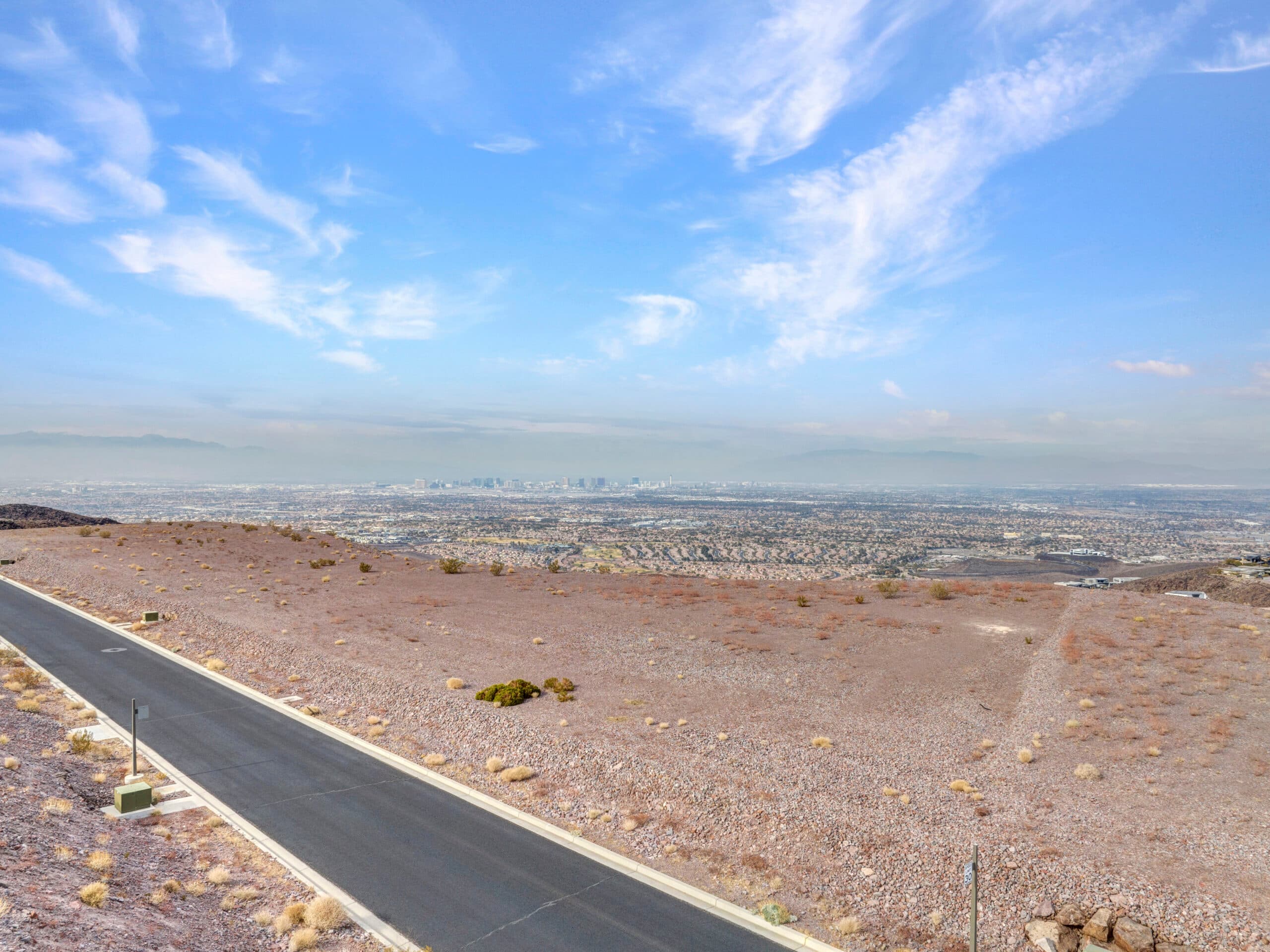 Expansive desert homesite with panoramic Las Vegas Strip and mountain views in luxury hillside community.