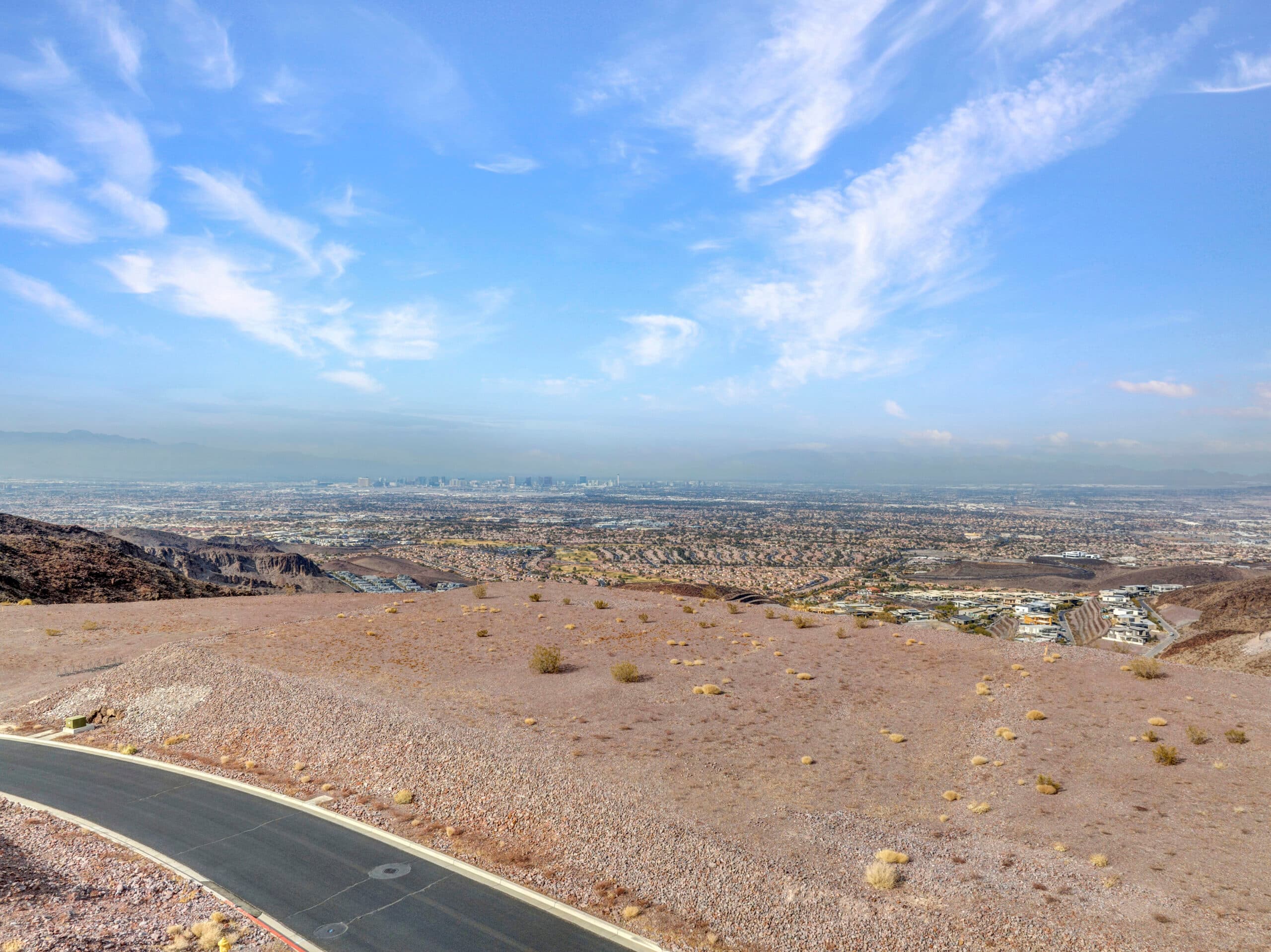 Expansive desert homesite with panoramic Las Vegas Strip and mountain views in luxury hillside community.