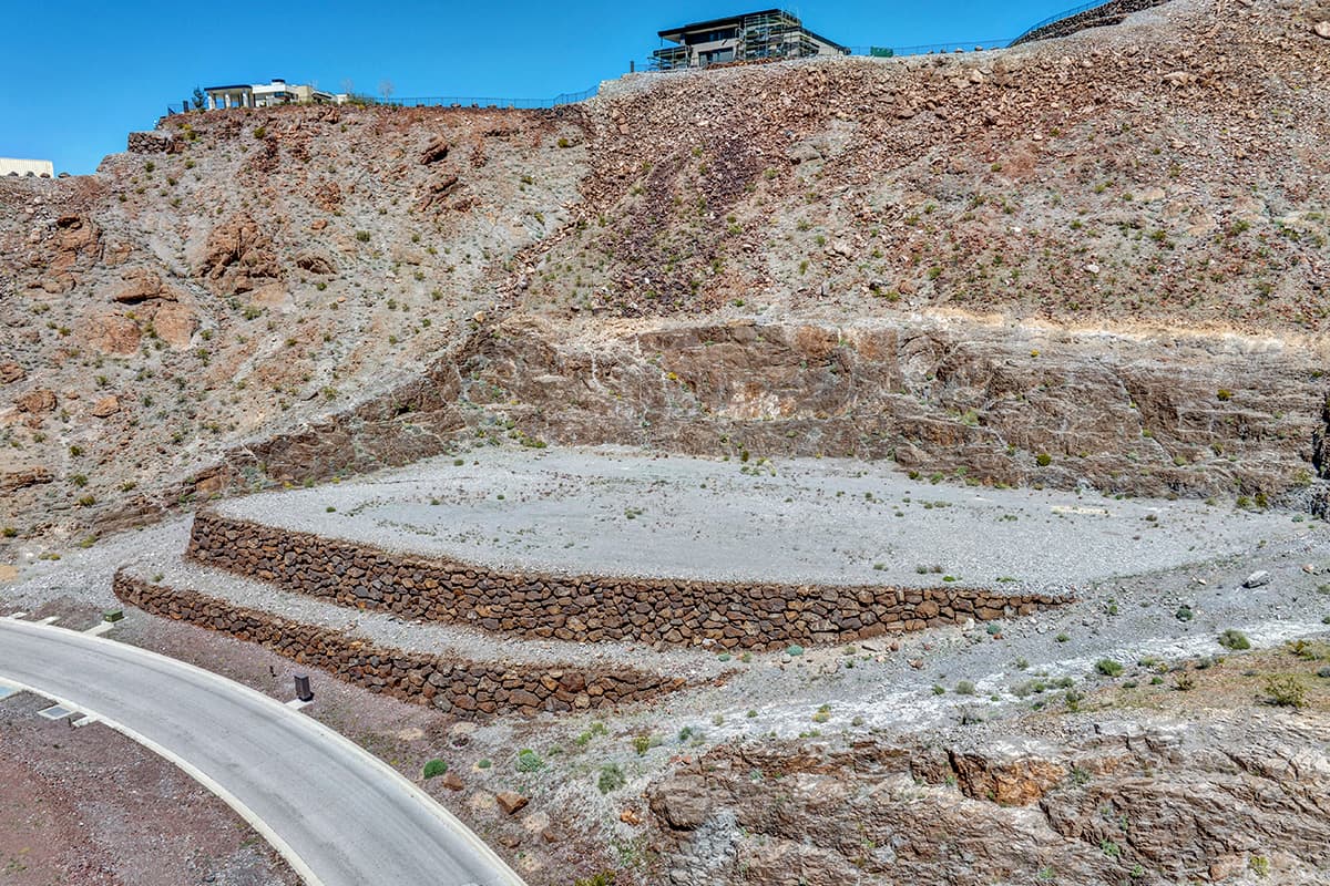 Custom luxury homesite carved into desert mountainside with stone retaining walls in Las Vegas hillside community.