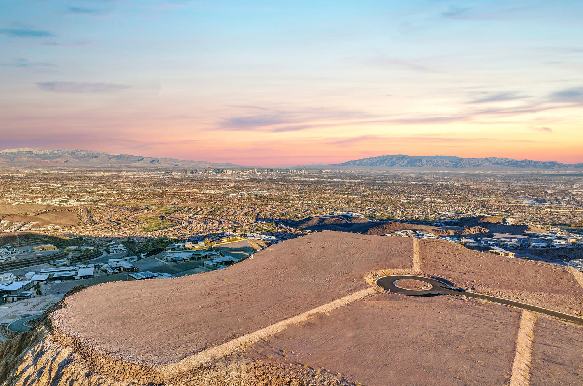 Elevated homesite at Ascaya overlooking the Las Vegas Valley, with panoramic city, mountain, and desert views stretching to the horizon at sunset.