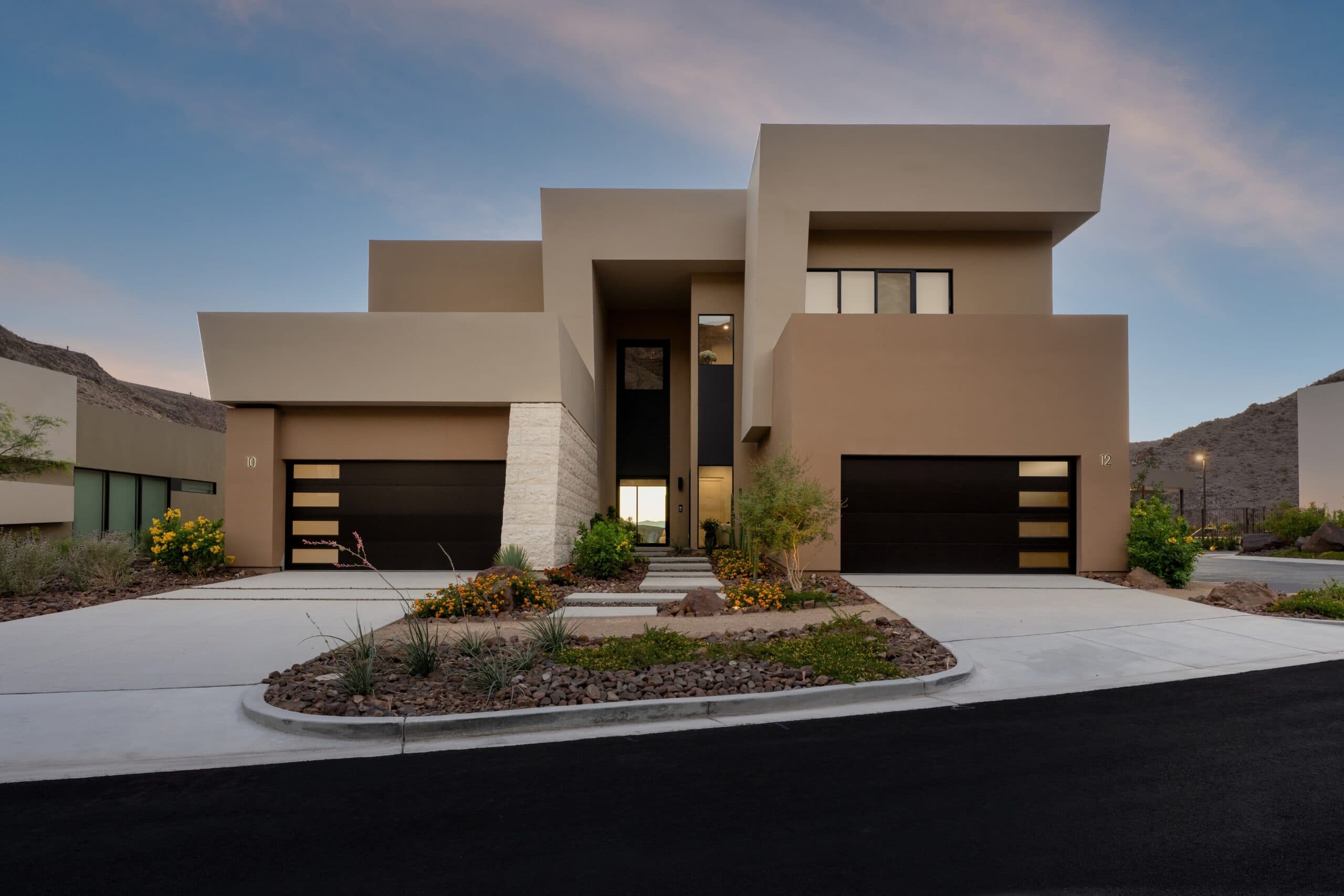 Modern luxury desert home exterior with bold geometric architecture, dual garages, and drought-tolerant landscaping.