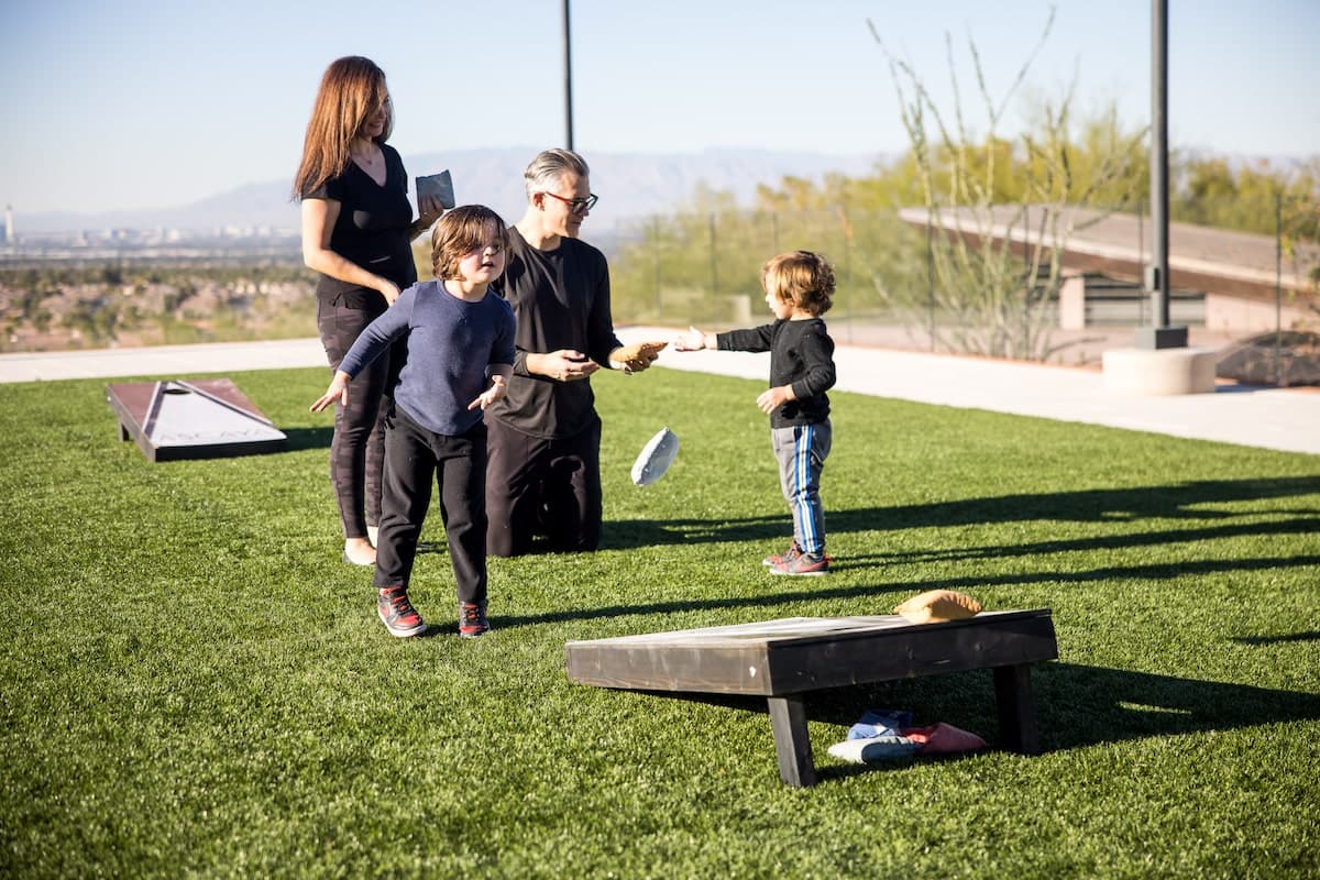 Family playing lawn games in luxury backyard setting.