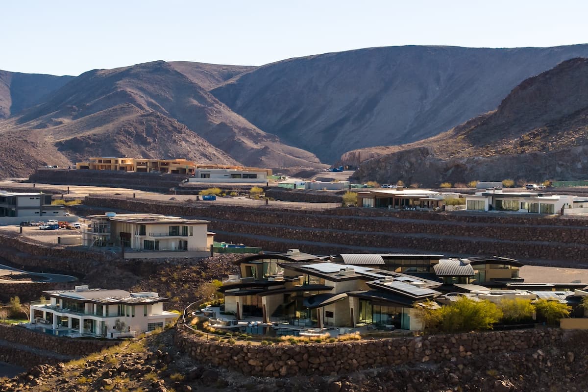 Modern homes and construction sites spread across terraced desert hills with expansive mountain views.