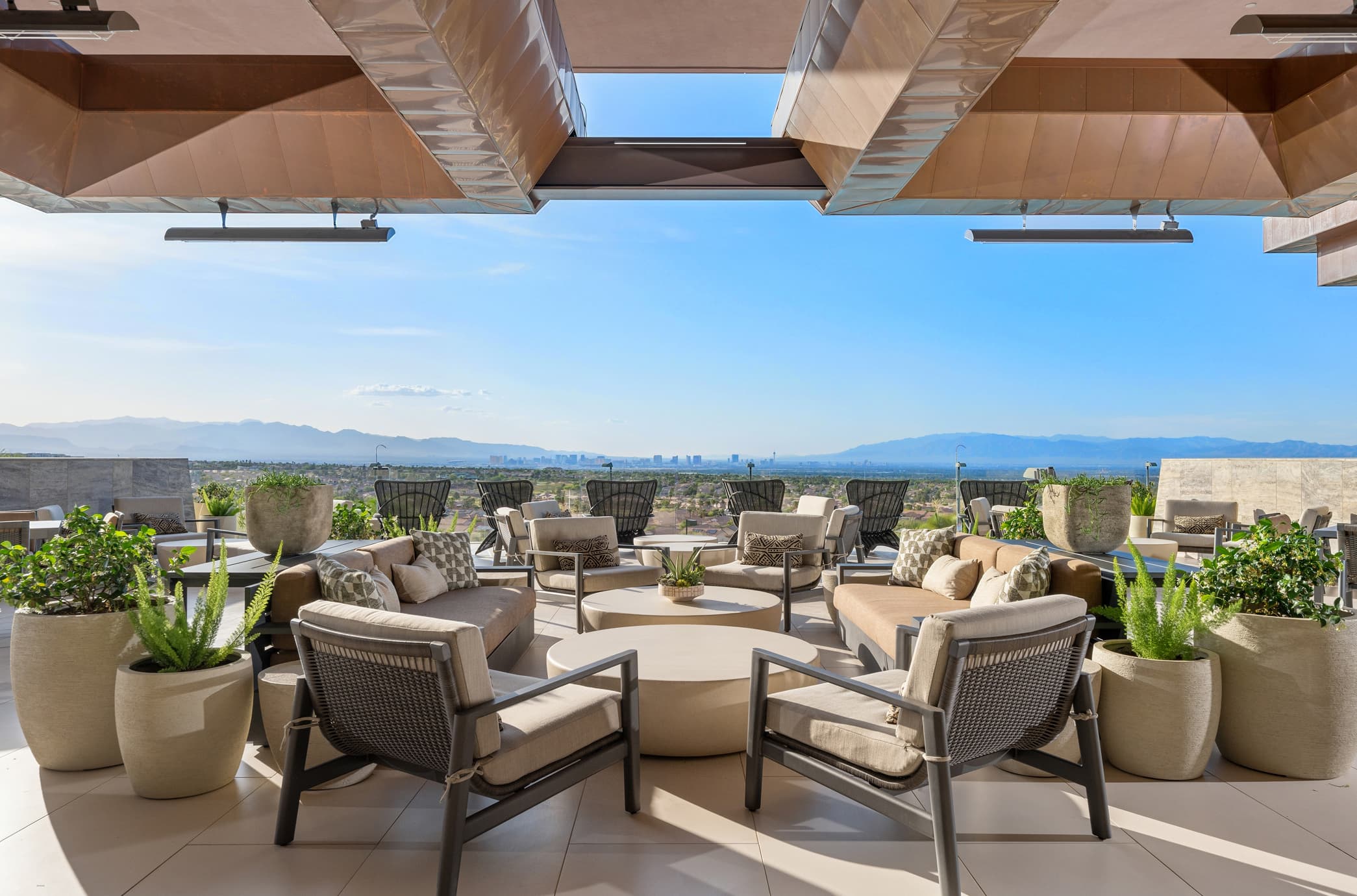 Luxury outdoor lounge terrace with modern seating, city skyline views, and desert landscape backdrop.