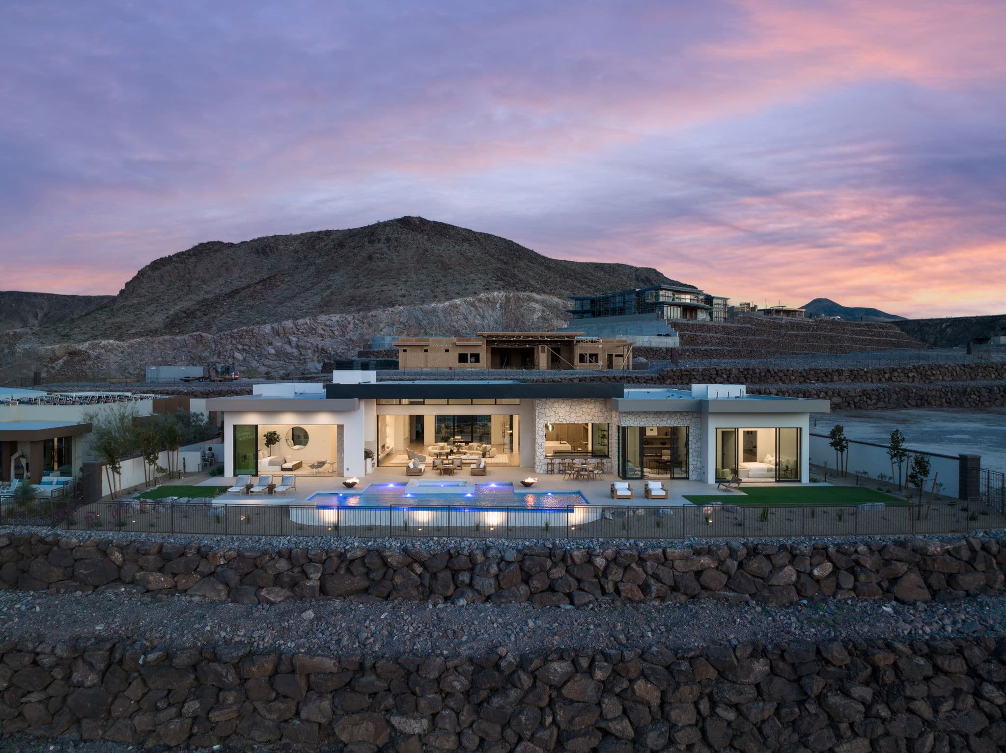 Modern luxury estate in Ascaya at sunset with resort-style pool, expansive indoor-outdoor living, and desert mountain backdrop