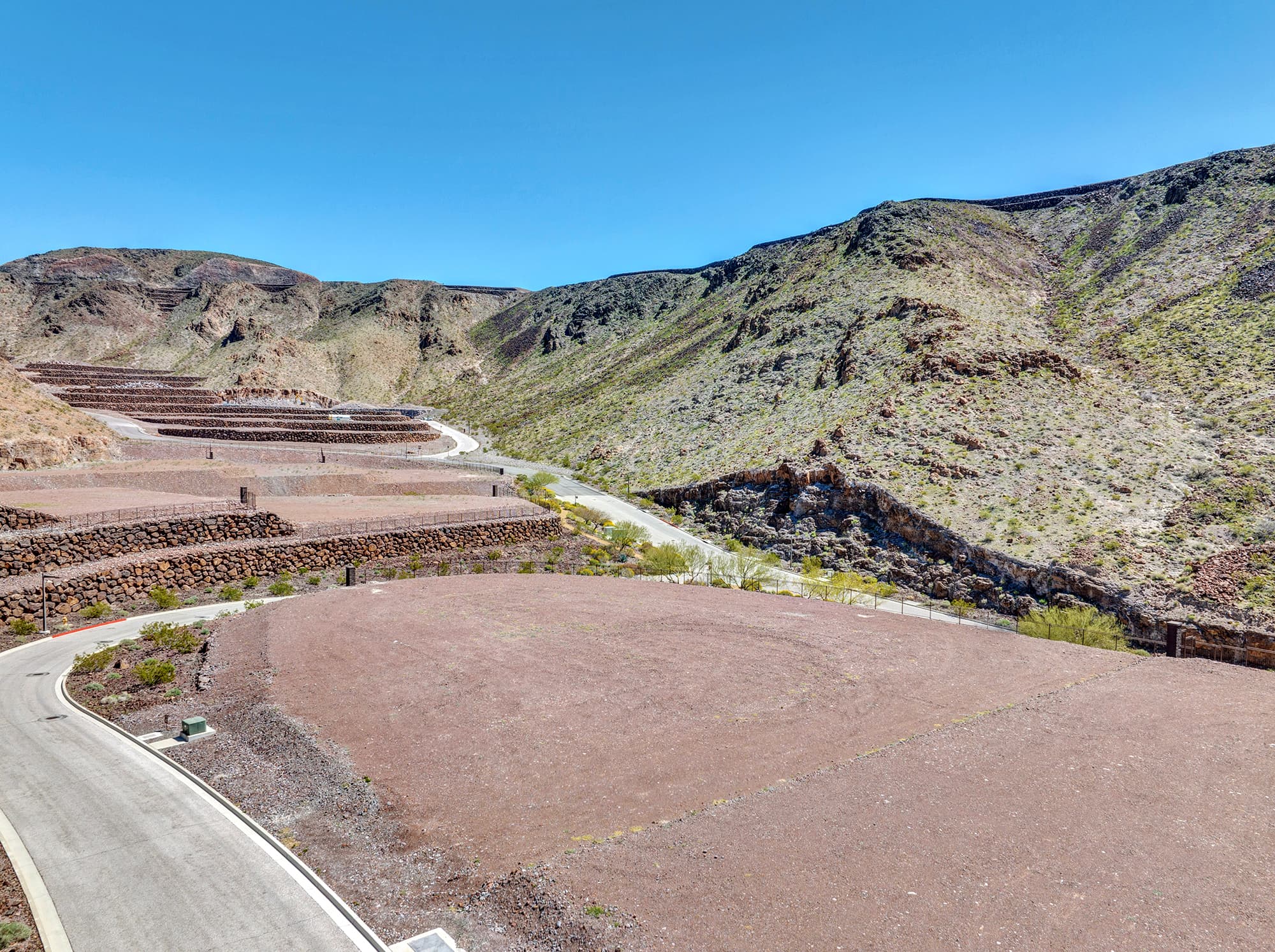 Aerial view of homesite lot outlined within a desert mountainside community development