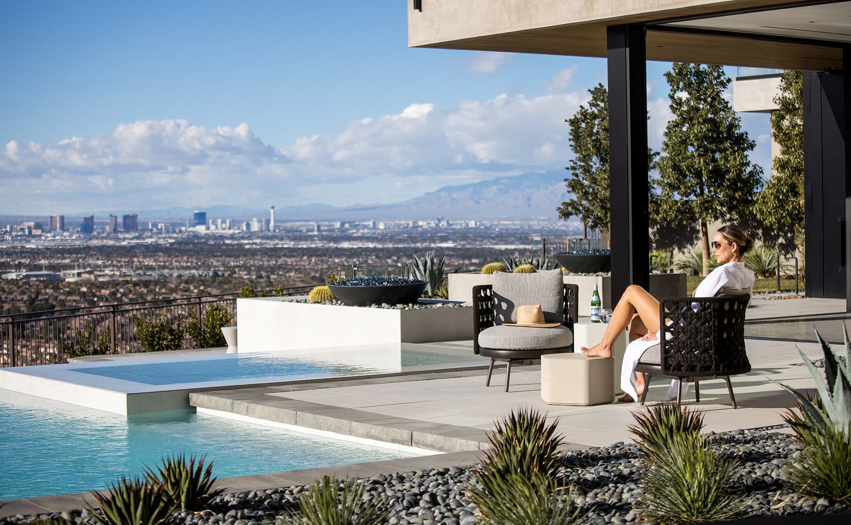 Woman relaxing on a luxury patio with pool overlooking Las Vegas skyline and mountain views.