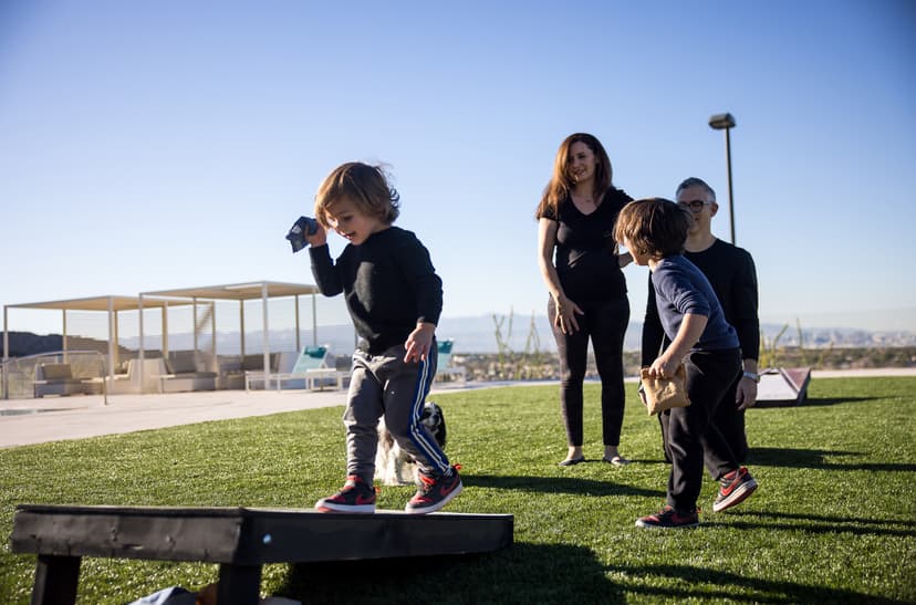 Family playing outdoor games on a landscaped lawn with modern amenities and scenic city views.