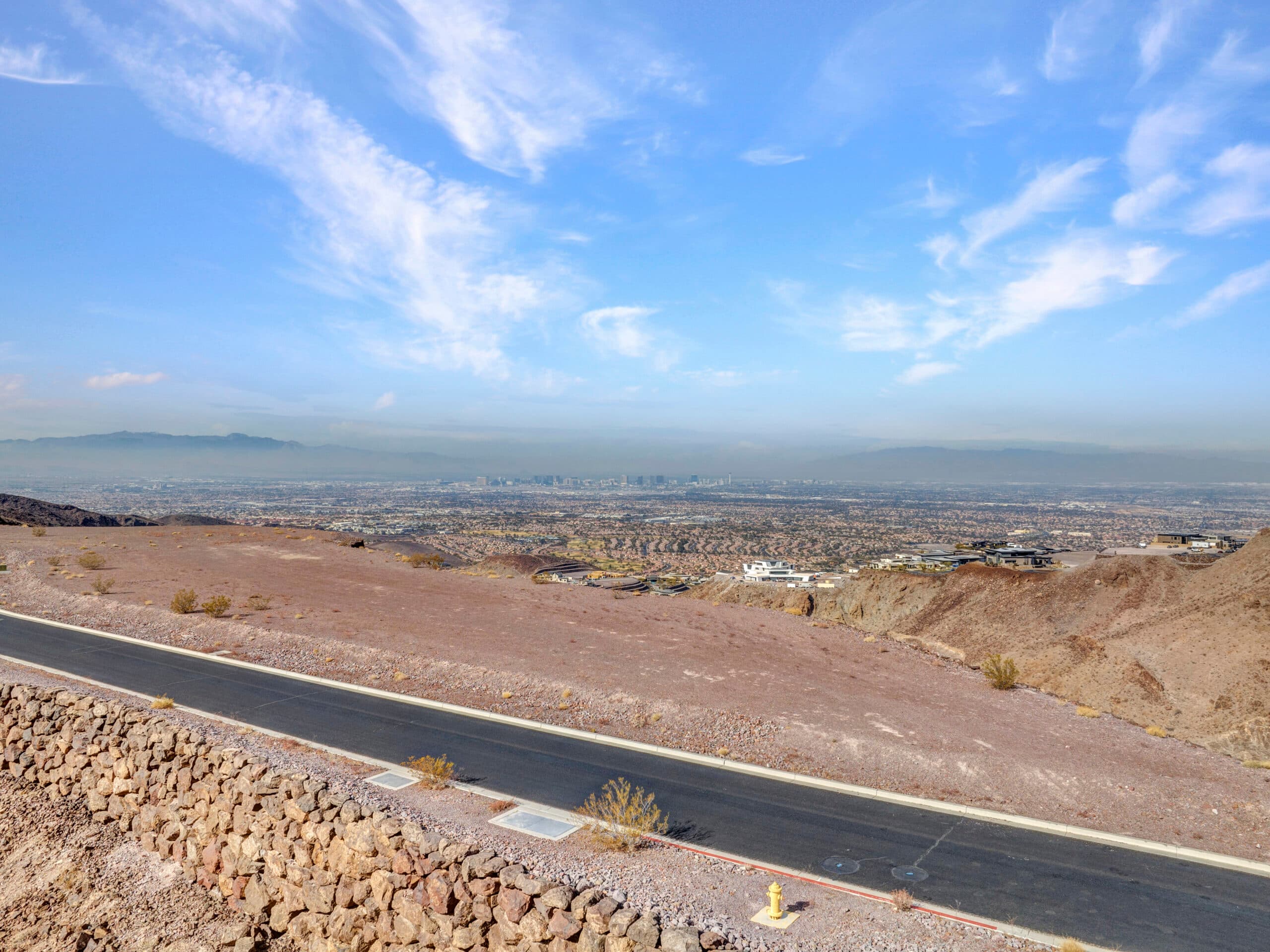 Expansive desert homesite with panoramic Las Vegas Strip and mountain views in luxury hillside community.