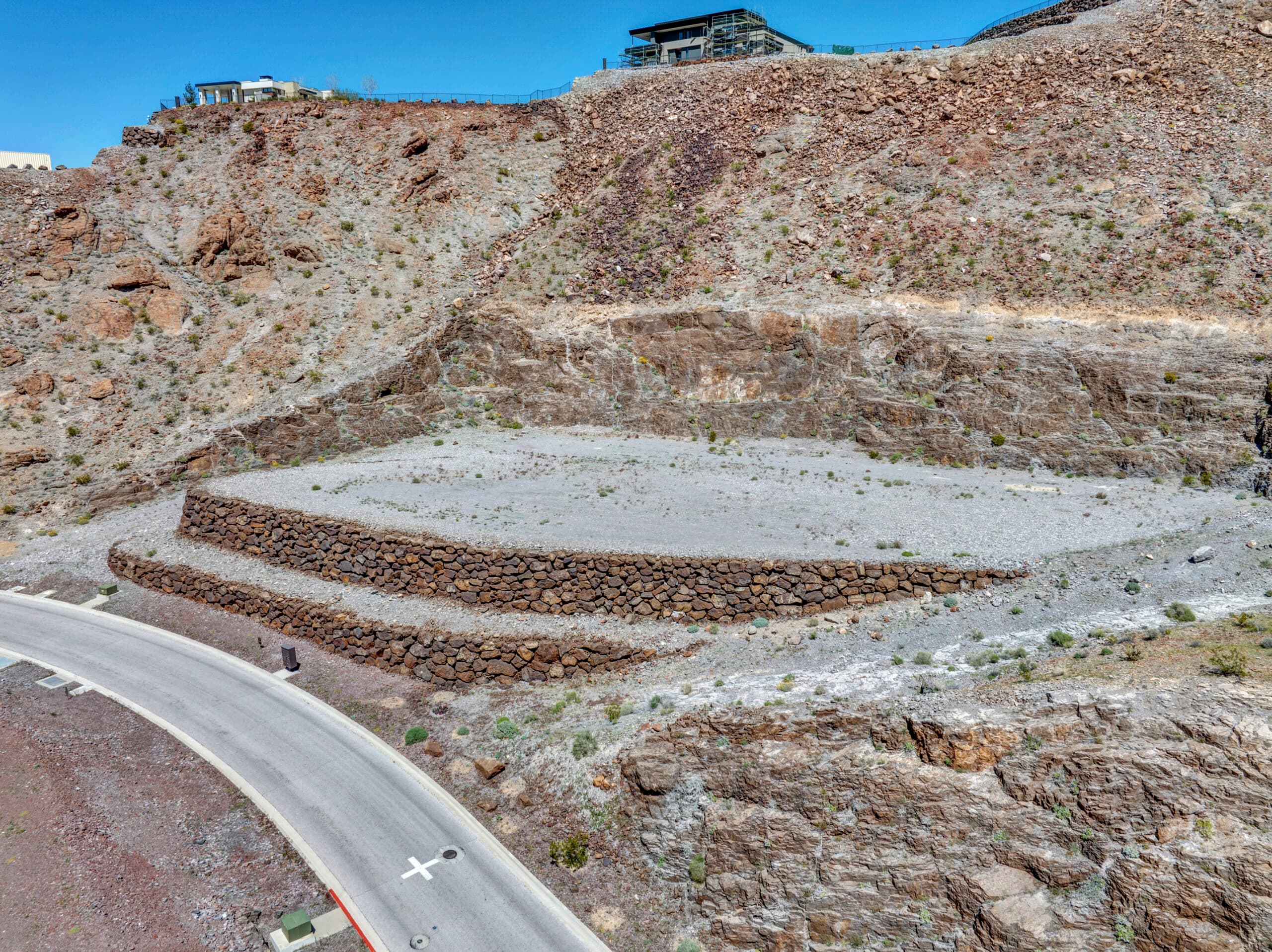 Custom luxury homesite carved into desert mountainside with stone retaining walls in Las Vegas hillside community.