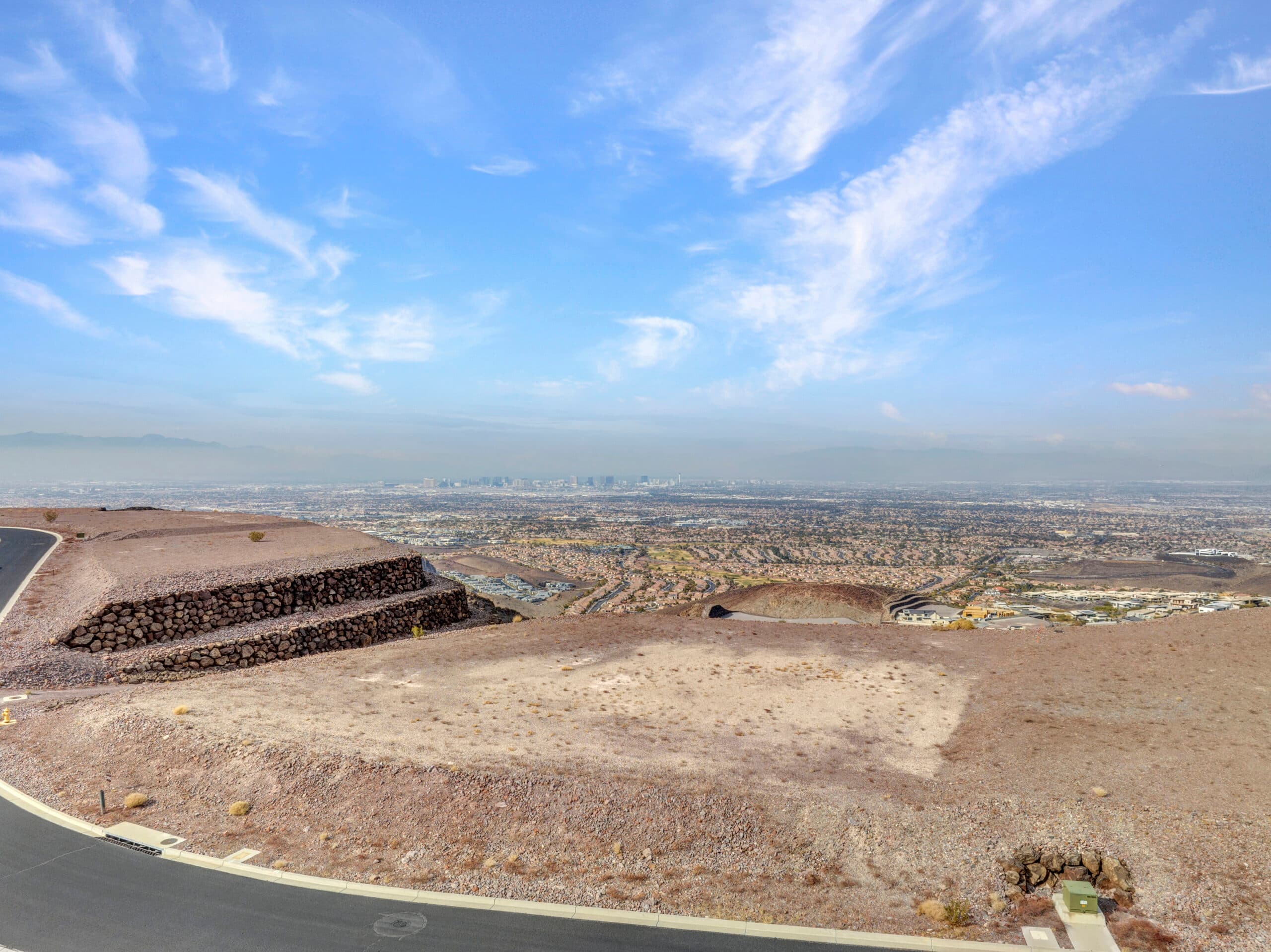 Expansive desert homesite with panoramic Las Vegas Strip and mountain views in luxury hillside community.