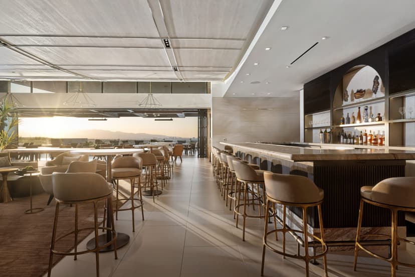 A stylish Ascaya clubhouse interior featuring a sleek bar, elegant seating, and an open-air design that flows onto a terrace with panoramic desert and mountain views.
