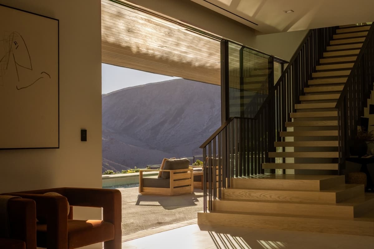 Modern luxury home interior with a floating staircase and panoramic desert mountain views.
