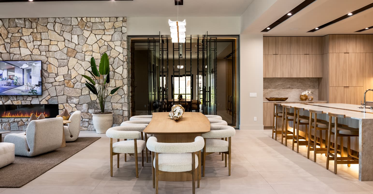 Contemporary open-concept dining and kitchen area with natural stone accents, custom wood cabinetry, oversized island seating, and modern designer furnishings