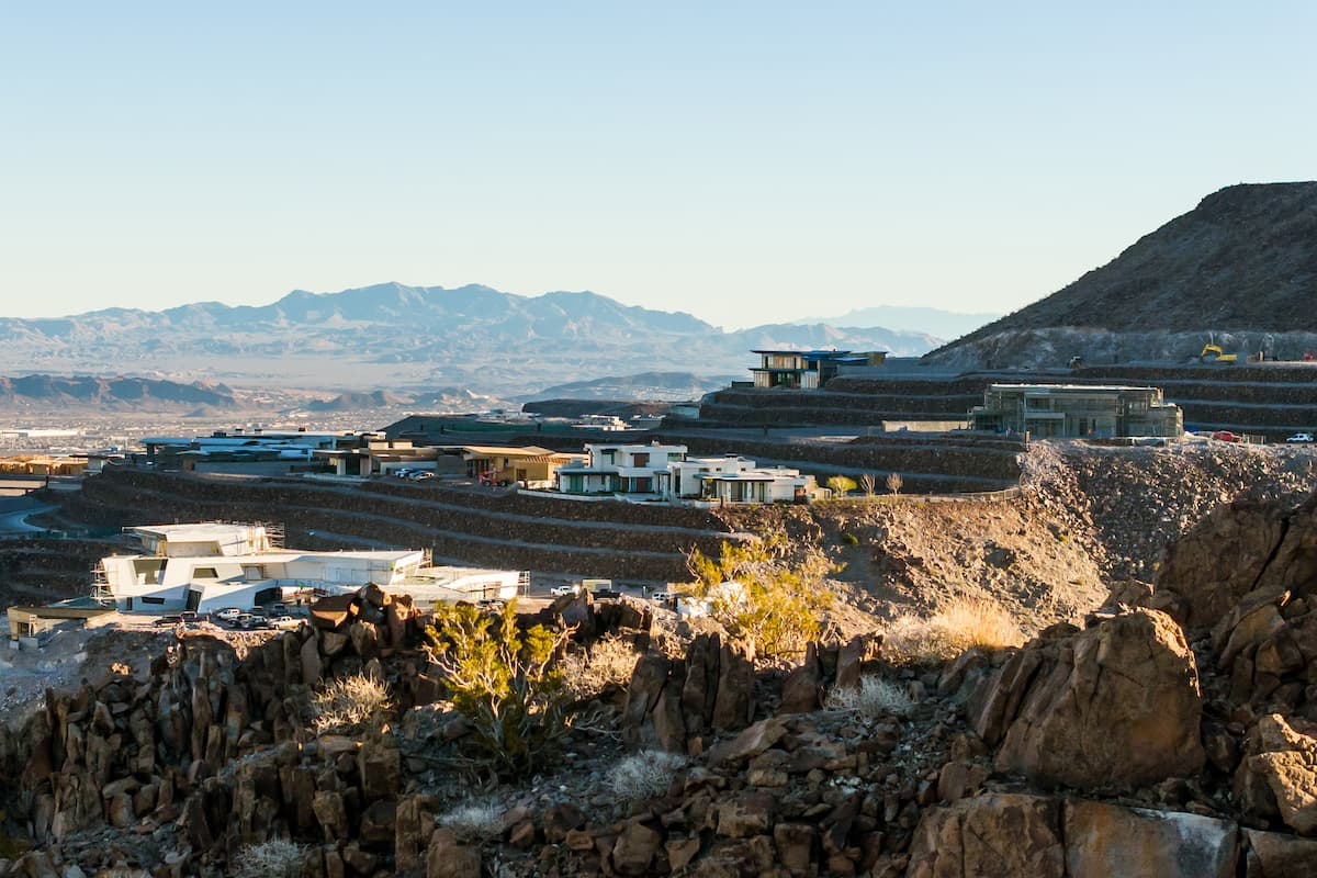 Modern homes and construction sites spread across terraced desert hills with expansive mountain views.
