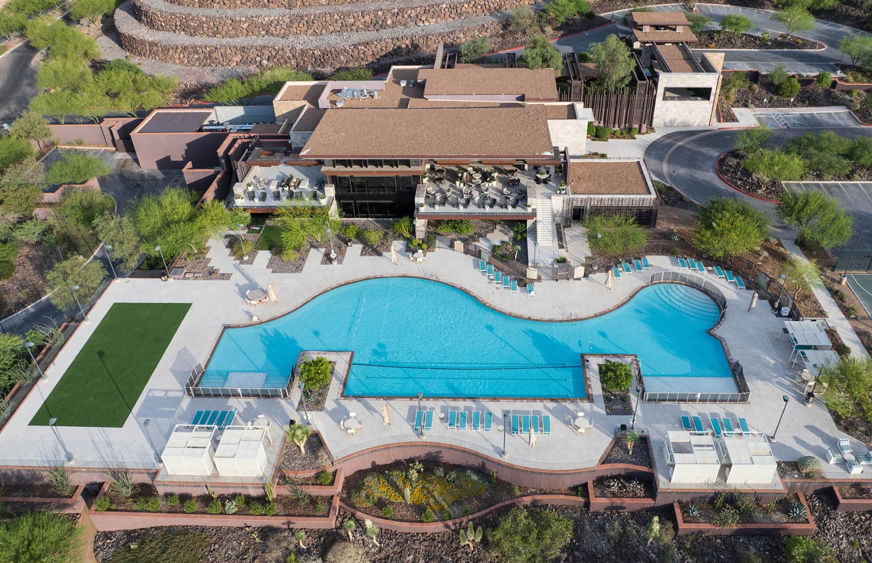 A serene zero-edge pool set against the rugged desert landscape, with crystal-clear water, private cabanas, and lounge seating framed by native greenery and mountain views.